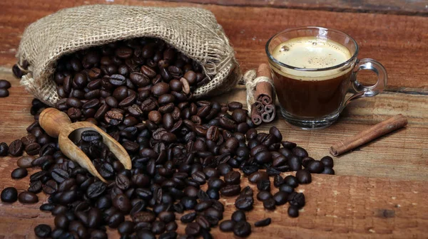 Taza de café con granos de café, saco de arpillera y con palitos de canela —  Fotos de Stock