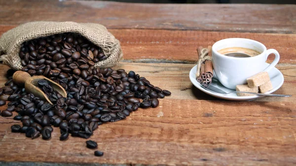 Taza de café con granos de café, saco de arpillera y con palitos de canela —  Fotos de Stock