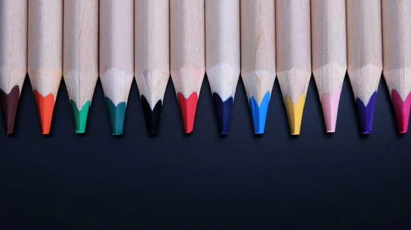 Colored pencils on a black background close-up in macro photography. — Stock Photo, Image