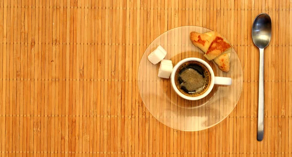 Rogalik i biały filiżankę kawy na talerzu — Zdjęcie stockowe