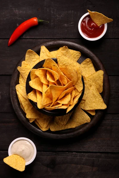 Mexican nachos in Wooden Bowl tortilla chips with chilli sauce, salsa and cheese dip, top view and Black Background — Stock Photo, Image