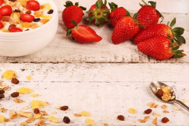 Beyaz ahşap arka planda, çilek ve granola müsli ile yoğurt kase.