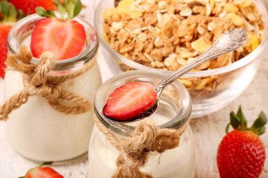 Lezzetli yoğurt ve çilek ve granola müsli ile kavanoz, ahşap masada beyaz üzerinde
