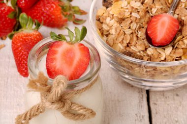 Lezzetli yoğurt ve çilek ve granola müsli ile kavanoz, ahşap masada beyaz üzerinde