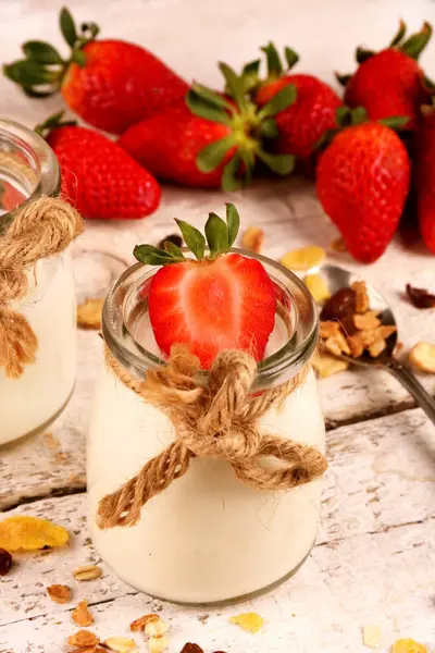 Βάζο με νόστιμο γιαούρτι και φράουλα και μούσλι, πάνω από ένα λευκό ξύλινο τραπέζι — Φωτογραφία Αρχείου