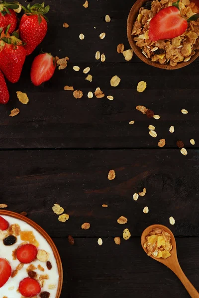 Beyaz ahşap arka planda, çilek ve granola müsli ile yoğurt kase.