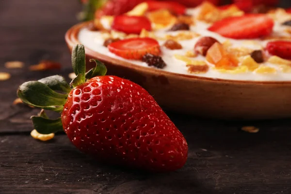 Beyaz ahşap arka planda, çilek ve granola müsli ile yoğurt kase.