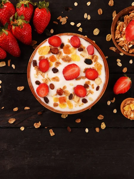 Beyaz ahşap arka planda, çilek ve granola müsli ile yoğurt kase.