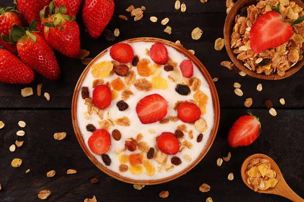 Beyaz ahşap arka planda, çilek ve granola müsli ile yoğurt kase.