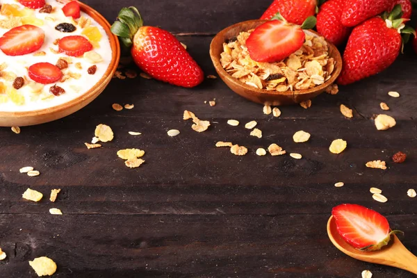 Beyaz ahşap arka planda, çilek ve granola müsli ile yoğurt kase.