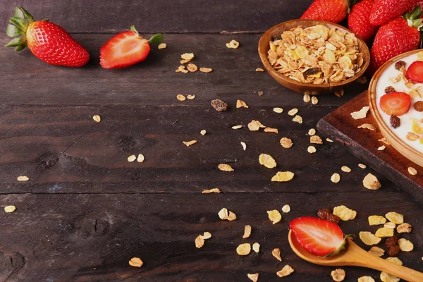 Beyaz ahşap arka planda, çilek ve granola müsli ile yoğurt kase.