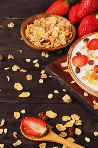 Beyaz ahşap arka planda, çilek ve granola müsli ile yoğurt kase.
