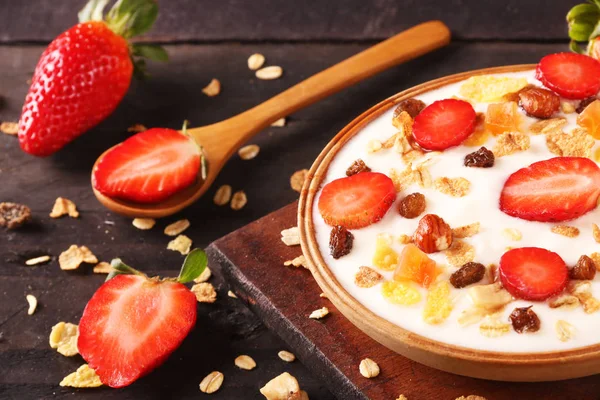 Beyaz ahşap arka planda, çilek ve granola müsli ile yoğurt kase.
