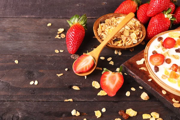 Beyaz ahşap arka planda, çilek ve granola müsli ile yoğurt kase.