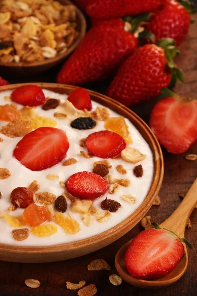Beyaz ahşap arka planda, çilek ve granola müsli ile yoğurt kase.