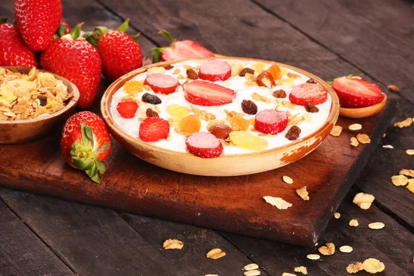 Beyaz ahşap arka planda, çilek ve granola müsli ile yoğurt kase.