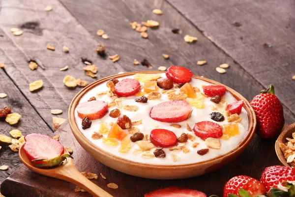 Beyaz ahşap arka planda, çilek ve granola müsli ile yoğurt kase.
