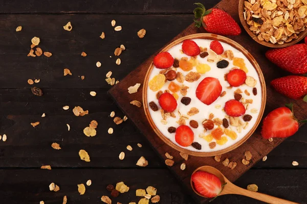 Beyaz ahşap arka planda, çilek ve granola müsli ile yoğurt kase.