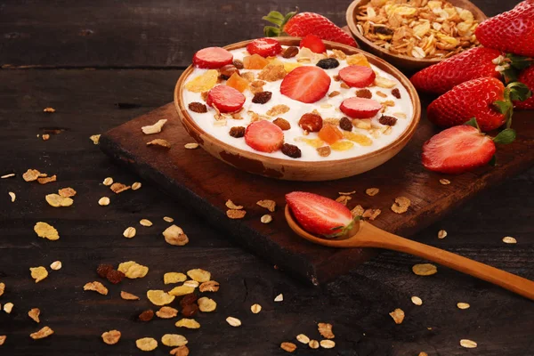 Beyaz ahşap arka planda, çilek ve granola müsli ile yoğurt kase.