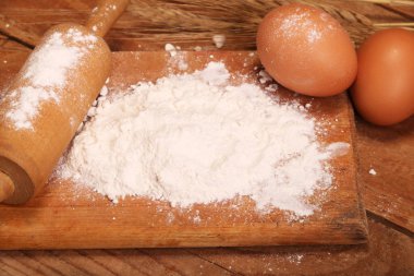 Mutfak haddeleme pin, ahşap arka planda un ile ahşap tahta, Masa üzerinde ekmek yapmak için kulakları ve yumurta.
