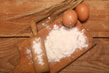 Mutfak haddeleme pin, ahşap arka planda un ile ahşap tahta, Masa üzerinde ekmek yapmak için kulakları ve yumurta.