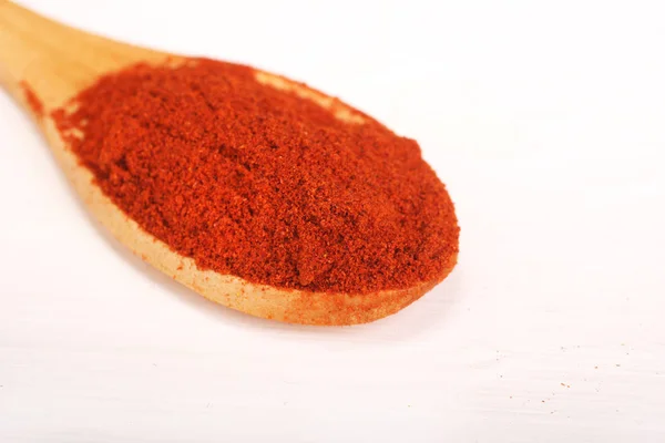 Ξύλινο κουτάλι που σερβίρει γεμάτο κόκκινο πιπέρι πάπρικα σκόνη μπαχαρικό απομονώνεται πάνω από το λευκό φόντο — Φωτογραφία Αρχείου