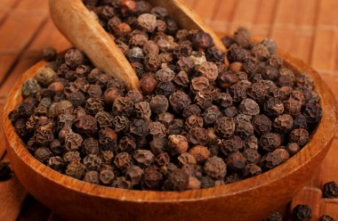 Ahşap arka planda izole ahşap kase karabiber baharat topları dolu ahşap servis kaşık kürek