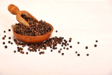 Beyaz arka planda izole ahşap kase karabiber baharat topları dolu ahşap servis kaşık kürek