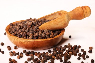 Beyaz arka planda izole ahşap kase karabiber baharat topları dolu ahşap servis kaşık kürek
