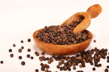 Beyaz arka planda izole ahşap kase karabiber baharat topları dolu ahşap servis kaşık kürek