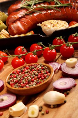 Sebze ve baharat ahşap arka plan üzerinde bir tavada ızgara sosis