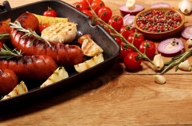 Sebze ve baharat ahşap arka plan üzerinde bir tavada ızgara sosis