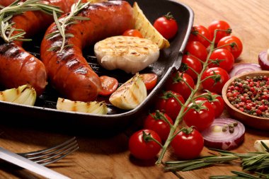 Sebze ve baharat ahşap arka plan üzerinde bir tavada ızgara sosis