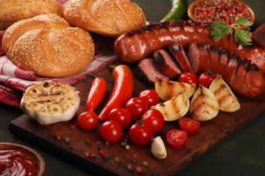 Ahşap kesme tahtası arka planda sebze, baharat ve ekmek ile ızgara sosis