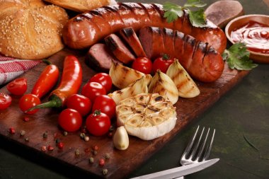 Ahşap kesme tahtası arka planda sebze, baharat ve ekmek ile ızgara sosis