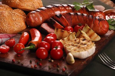 Ahşap kesme tahtası arka planda sebze, baharat ve ekmek ile ızgara sosis