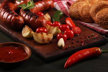 Ahşap kesme tahtası arka planda sebze, baharat ve ekmek ile ızgara sosis