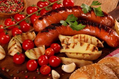 Ahşap kesme tahtası arka planda sebze, baharat ve ekmek ile ızgara sosis