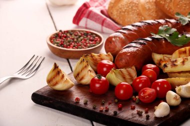 Ahşap kesme tahtası arka planda sebze, baharat ve ekmek ile ızgara sosis