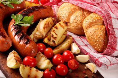 Ahşap kesme tahtası arka planda sebze, baharat ve ekmek ile ızgara sosis