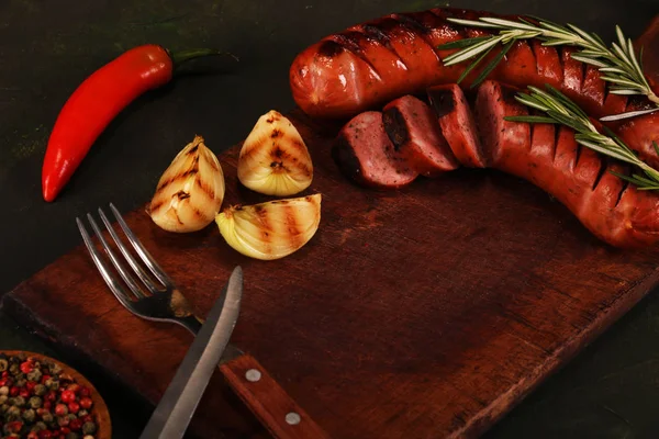 Grillwürste mit Gemüse, Gewürzen und Brot auf Holzschneidebrett Hintergrund — Stockfoto