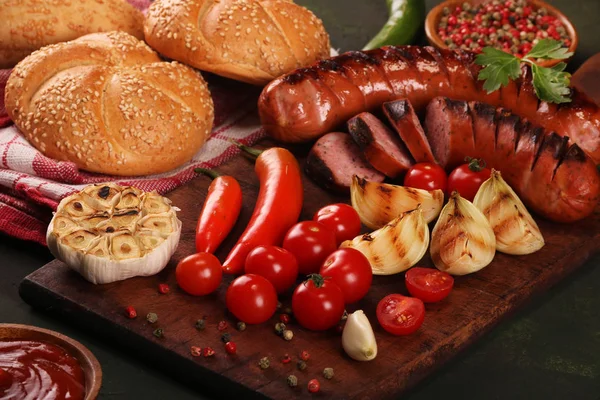 Ahşap kesme tahtası arka planda sebze, baharat ve ekmek ile ızgara sosis