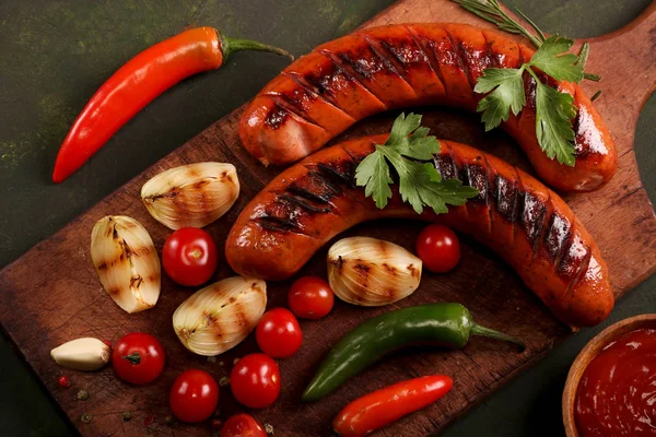 Embutidos a la parrilla con verduras, especias y pan sobre fondo de tabla de cortar de madera —  Fotos de Stock