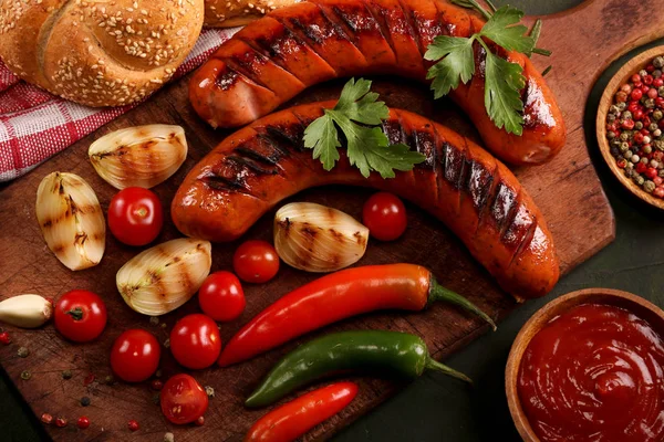 Ahşap kesme tahtası arka planda sebze, baharat ve ekmek ile ızgara sosis