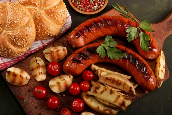Ahşap kesme tahtası arka planda sebze, baharat ve ekmek ile ızgara sosis. Üstte görüntü