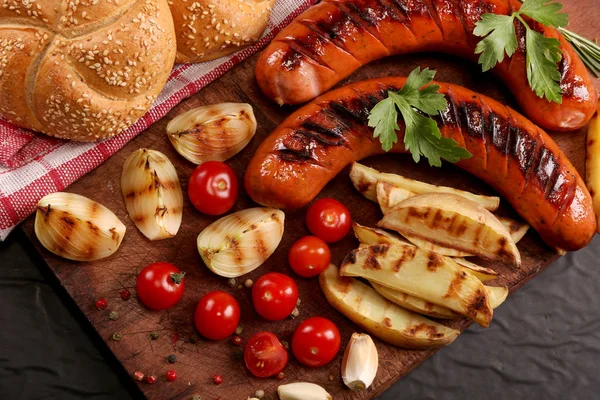 Ahşap kesme tahtası arka planda sebze, baharat ve ekmek ile ızgara sosis. Üstte görüntü