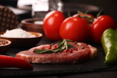 Sebze, biber, domates, tuz, biberiye ve baharat taş masa üzerinde pişirme ile Çiğ domuz eti biftek. Üstte görüntü.