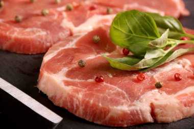 Sebze, biber, domates, tuz, biberiye ve baharat taş masa üzerinde pişirme ile Çiğ domuz eti biftek. Üstte görüntü.