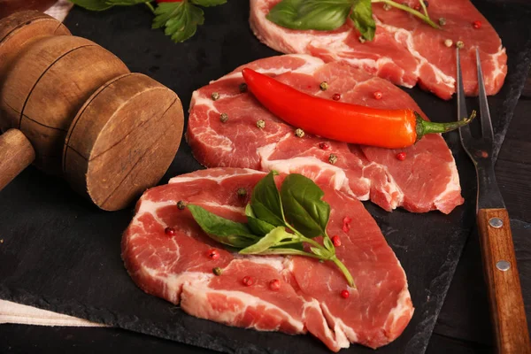 Filete crudo de carne de cerdo con verduras, pimientos, tomate, sal, romero y especias que se cocinan sobre una mesa de piedra. Vista superior . — Foto de Stock