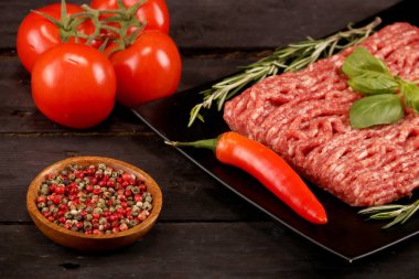 kağıt üzerinde çiğ kıyma, siyah arka plan üzerinde domates, biber, soğan, baharat ve baharat ile burger için malzemeler